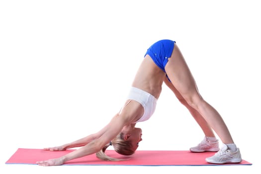 Flexible woman doing stretching exercises on mat in studio