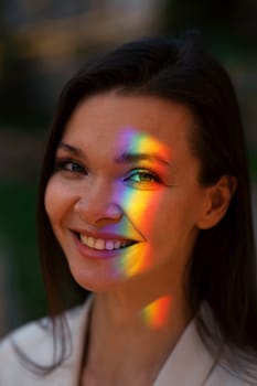 Portrait of caucasian woman with rainbow beam on her face outdoors