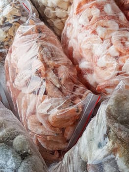 There are many large plastic bags with frozen raw and boiled shrimp on the counter of the fish market