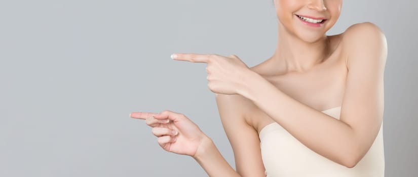 Closeup glamorous beautiful woman with perfect makeup clean skin pointing finger in copyspace isolated background. Promotion indicated by hand gesture concept for skincare product advertisement.