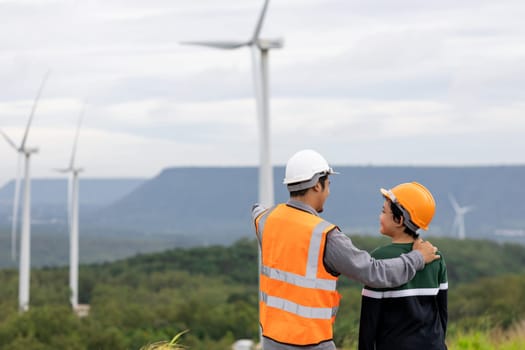 Engineer with his son on a wind farm atop a hill or mountain in the rural. Progressive ideal for the future production of renewable, sustainable energy. Energy generation from wind turbine.