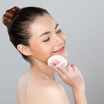 Glamorous beautiful female model applying cushion powder for facial makeup concept. Portrait of flawless perfect cosmetic skin woman put powder puff on her face in isolated background.