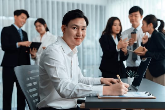 Portrait of focus young successful confident male manager, executive wearing business wear in harmony office arm crossed with blurred meeting background of colleagues, office worker.