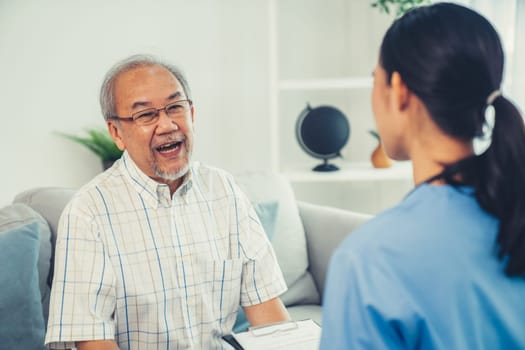 Caring young female doctor examining her contented senior patient with stethoscope in living room. Medical service for elderly, elderly sickness, declining health.