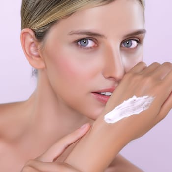 Alluring beautiful woman applying moisturizer cream on her hand for perfect skincare treatment in pink isolated background. Caucasian women portrait with skin rejuvenation and cosmetology concept.