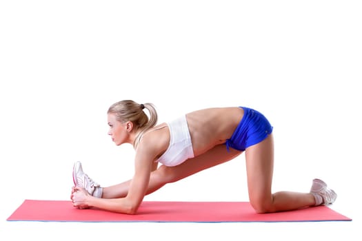Pretty blonde doing aerobics exercises on mat, isolated over white background