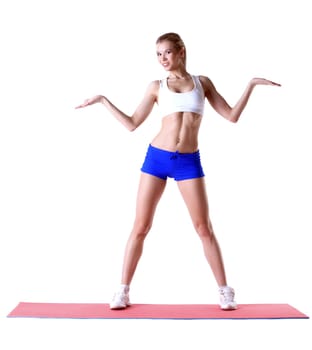 Cheerful slim woman posing on mat in studio, isolated over white background