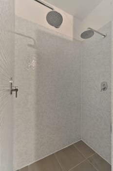 a white tiled bathroom with shower head and hand held fauced on the wall in front of the tub