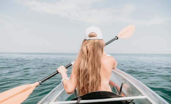 Woman in kayak back view. Happy young woman with long hair floating in transparent kayak on the crystal clear sea. Summer holiday vacation and cheerful female people having fun on the boat.