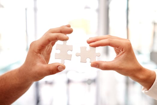 Where there are problems, we should come together to solve it. Closeup shot of two unrecognisable businesspeople holding puzzle pieces together