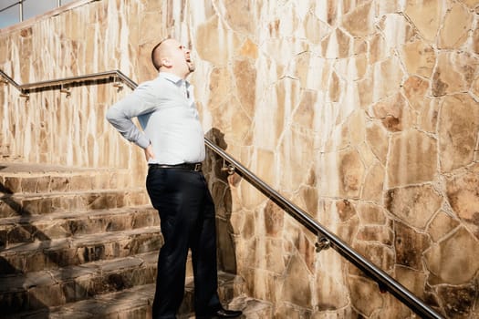 Portrait of a senior professional man in a suit with various problems. A middle-aged businessman with a briefcase descends the stairs.