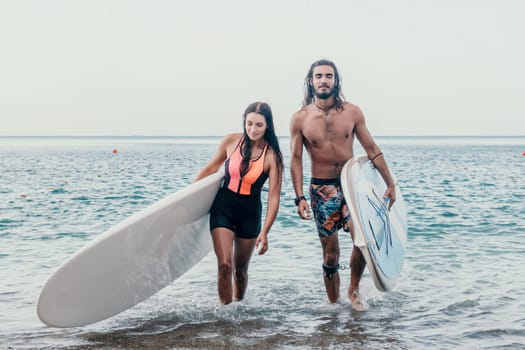 Sea woman and man on sup. Silhouette of happy young woman and man, surfing on SUP board, confident paddling through water surface. Idyllic sunset. Active lifestyle at sea or river