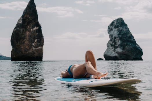 Close up shot of beautiful young caucasian woman with black hair and freckles looking at camera and smiling. Cute woman portrait in a pink bikini posing on a volcanic rock high above the sea