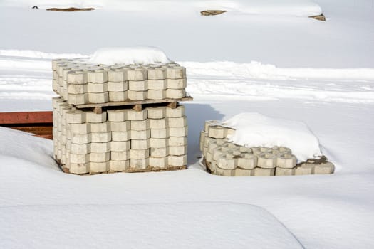 a stack of paving slabs on a construction site covered with snow. Construction and landscaping. High quality photo