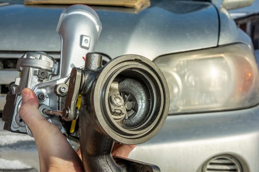 A turbine for an automobile engine in the hands of an auto mechanic on the background of a car. Maintenance and repair of the car in the car service.