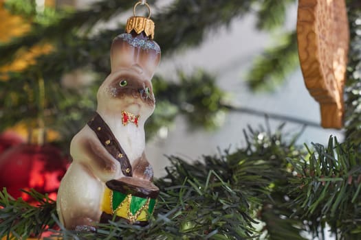 A glass Christmas tree toy hare with a drum on the background of an artificial Christmas tree. New Year's celebration. A family holiday.