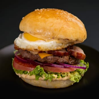 Big tasty burger with beef cutlet on a black background