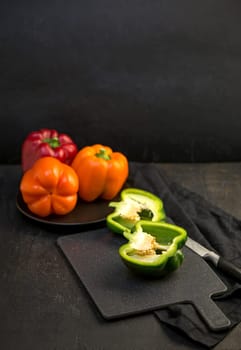 colored peppers on black background