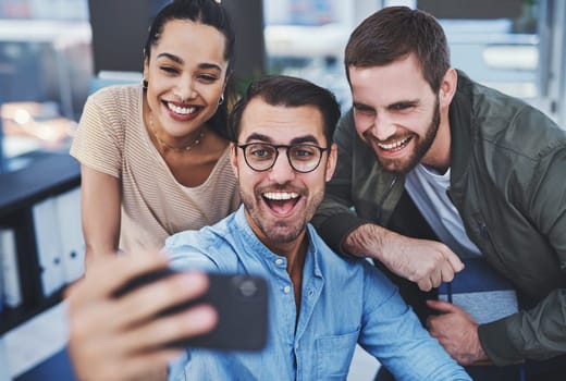 We have fun while working hard. a group of designers taking selfies together in an office