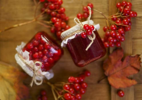 Viburnum fruit jam in a glass jar on a wooden table, preparations for the winter