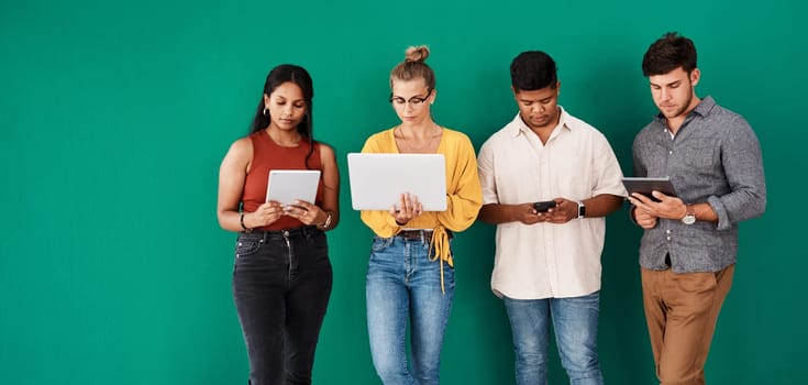 Stay connected to your office with the right business tools. a group of young designers using digital devices while standing together against a green background