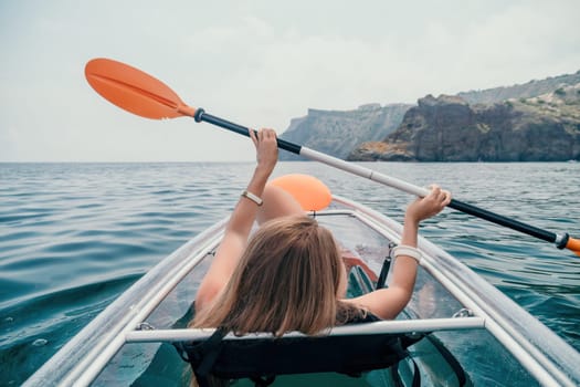 Woman in kayak back view. Happy young woman with long hair floating in transparent kayak on the crystal clear sea. Summer holiday vacation and cheerful female people having fun on the boat.