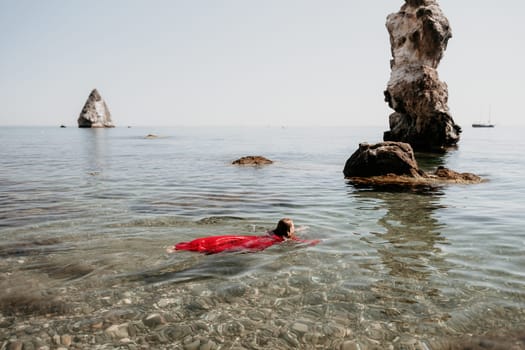 Woman travel sea. Happy tourist taking picture outdoors for memories. Woman traveler looks at the edge of the cliff on the sea bay of mountains, sharing travel adventure journey.