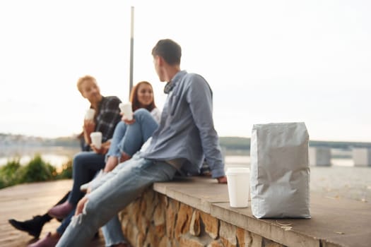 Coffee package. Group of young cheerful friends that is outdoors having fun together.