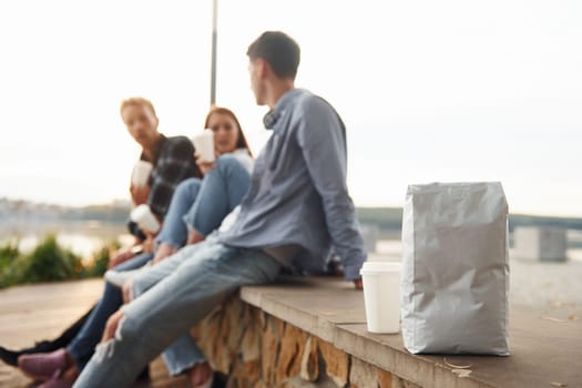 Coffee package. Group of young cheerful friends that is outdoors having fun together.