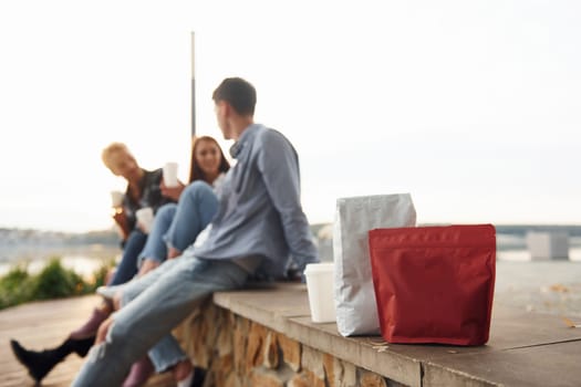 Coffee packages. Group of young cheerful friends that is outdoors having fun together.