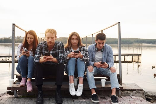 Near the lake. Group of young cheerful friends that is outdoors having fun together.