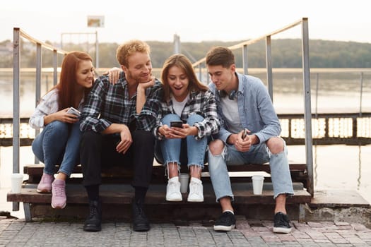 Near the lake. Group of young cheerful friends that is outdoors having fun together.