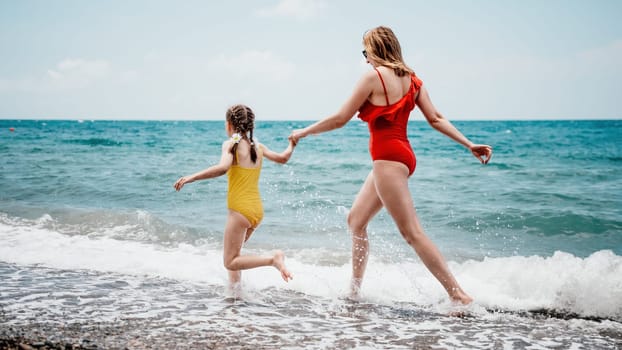 Happy loving family mother and daughter having fun together on the beach. Mum playing with her kid in holiday vacation next to the ocean - Family lifestyle and love concept.