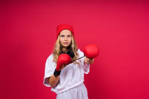 Cute little girl in boxing gloves on a red background studio