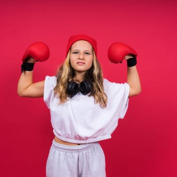 Cute little girl in boxing gloves on a red background studio