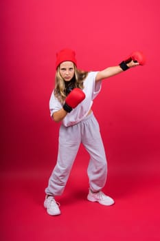 Cute little girl in boxing gloves on a red background studio