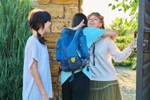 Meeting of friends, young female with guy and girl joyfully hugging near front door to yard. Welcome, youth, friendship, students, lifestyle concept