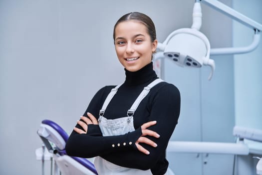 Portrait of young smiling teen girl in dental office looking at camera. Teenage female patient on examination treatment. Adolescence, hygiene, dental health care