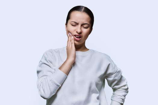 Teenage girl having toothache, on white studio background. Dental health, teenagers, young people concept