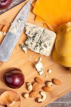 Cheese with nuts and fruits on wooden background. Over top view