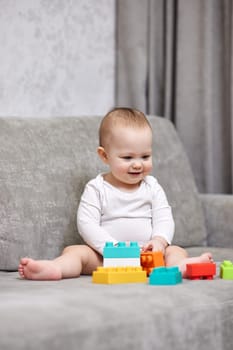cute baby girl playing with colorful toy blocks at home