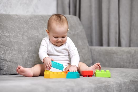 cute child girl playing with colorful toy blocks at home