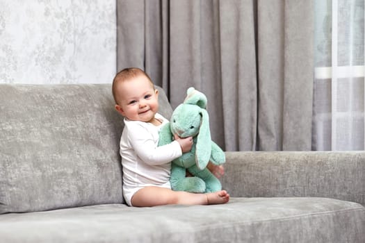 cute baby girl playing with soft toy bunny at home.