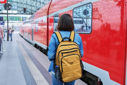 Eletro train, railway station inside, peron, woman passenger back view. Transport, city, passenger transportation urban concept