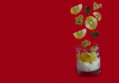 Yoghurt dessert with kiwi fruits and granola ships served in glass. levitating objects, copy space