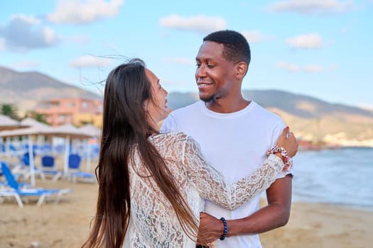 Beautiful young couple in love on beach. Portrait of Asian woman and African American man looking at each other. Multicultural, multiethnic family, relationships, togetherness, lifestyle, sea nature vacation