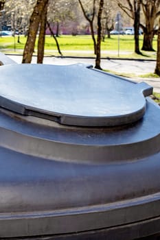 Large gray plastic trash can in the park close up