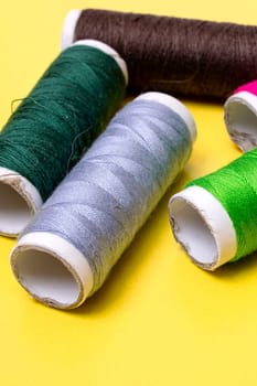 Coils with multicolored threads on a yellow background close up