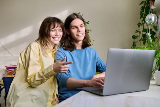 Teenage friends male and female using laptop at home for leisure. Youth, lifestyle, communication, friendship, technology, young people concept