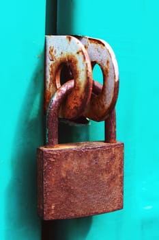 Old rusty padlock on a green door close up